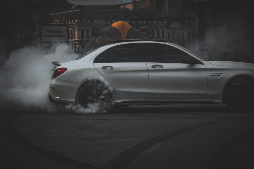 White sports car drifting on a dark road at night with tire smoke - High-oerformance vehicle in action